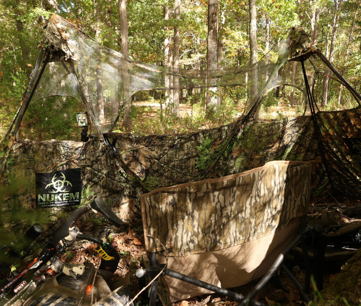 Camo hunting blind with mesh cover and chair in forest, ideal for deer hunting and wildlife observation