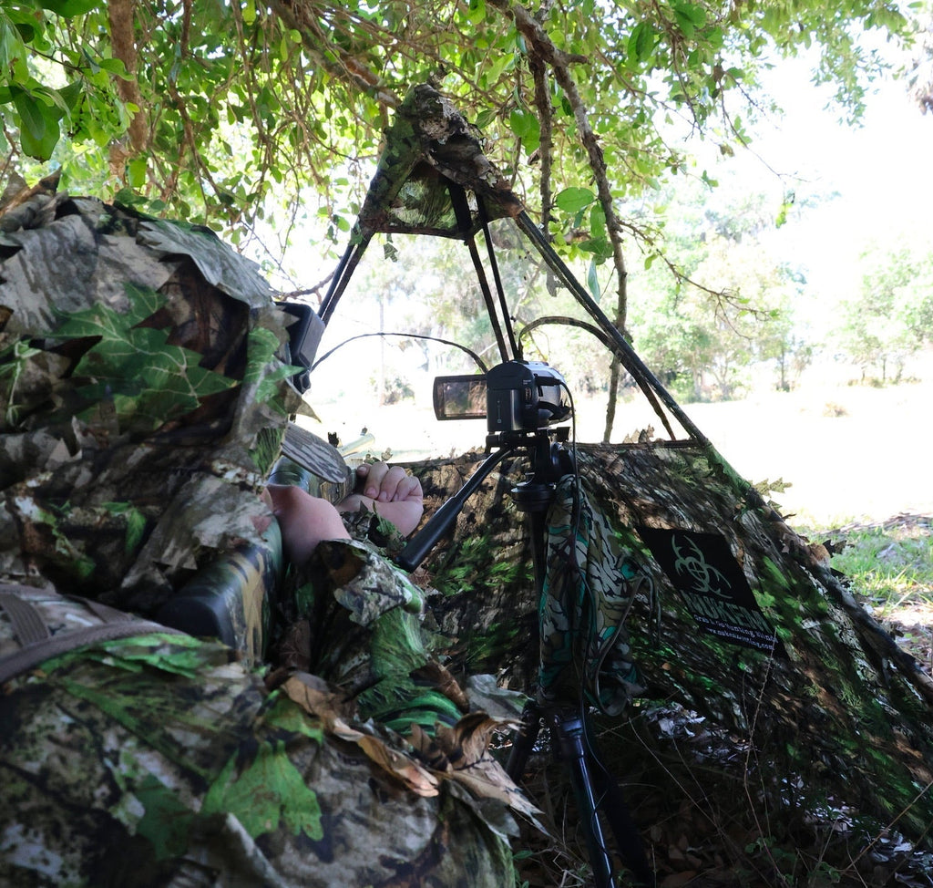 Camouflage hunting blind with leafy pattern, ideal for deer hunting and wildlife observation in dense woods.