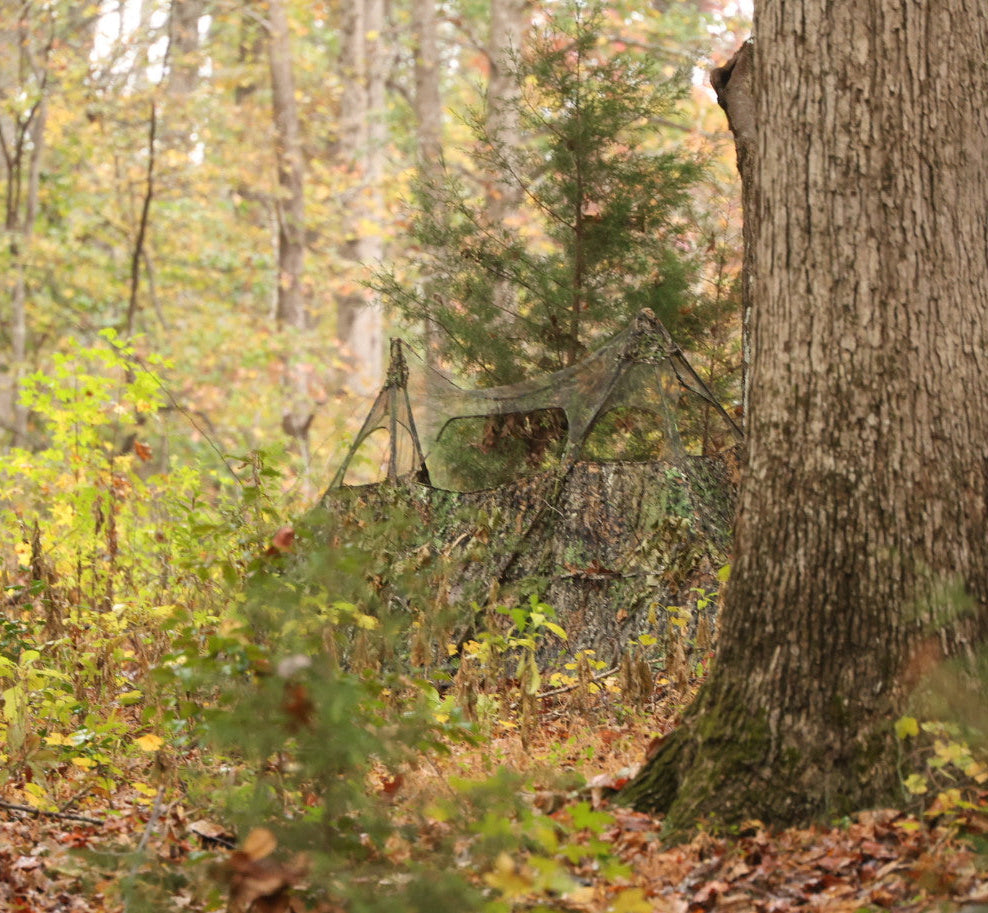 Camo hunting blind in autumn forest, blending with trees for deer hunting concealment