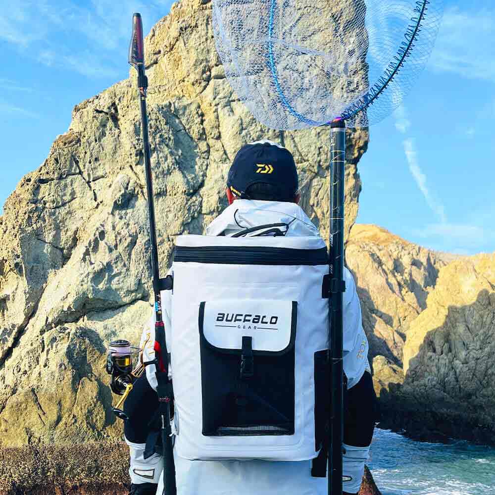 White Buffalo Gear fishing backpack with rod holders, worn by angler near rocky coast