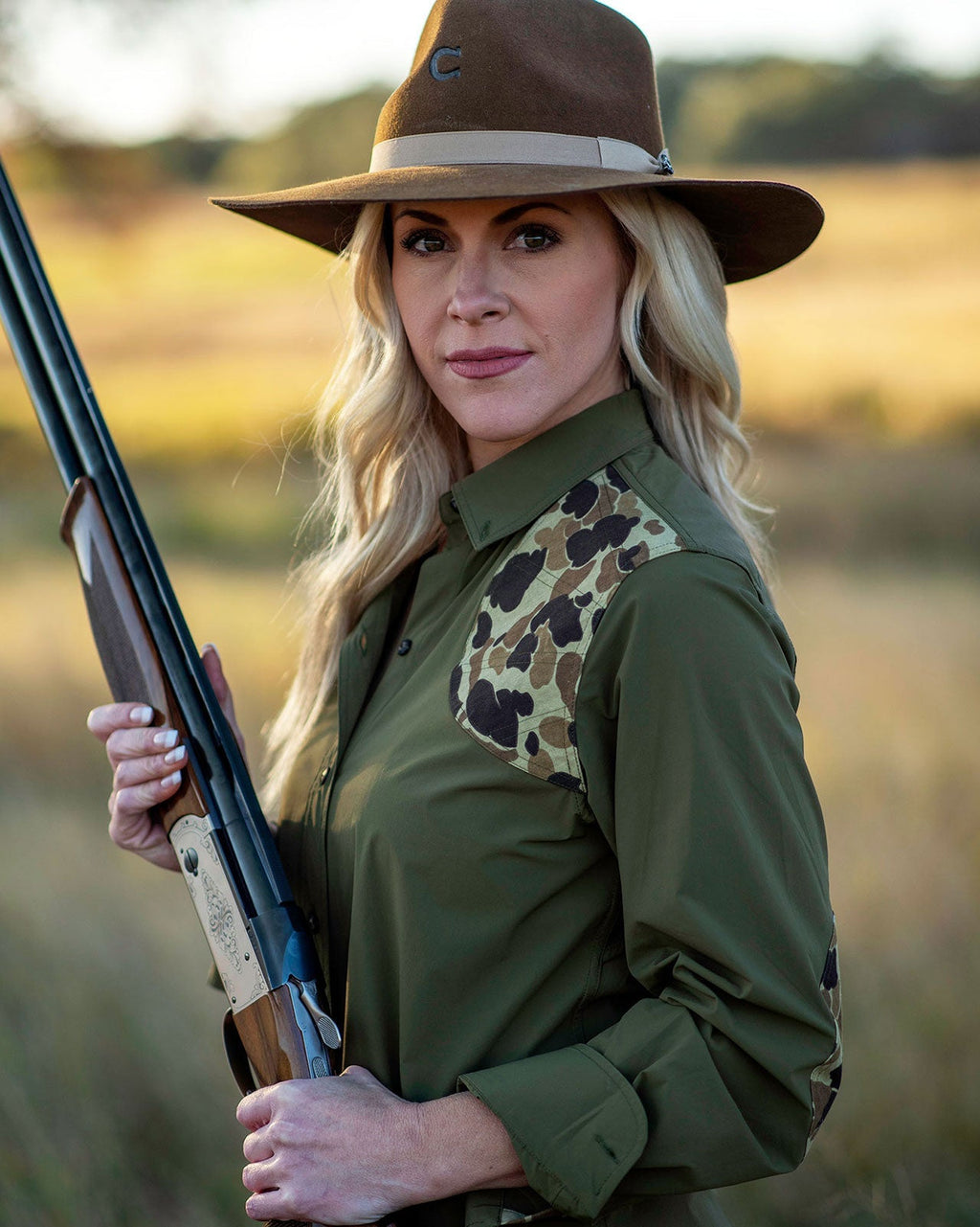 Woman in a felt hat holding a shotgun while wearing the Olive Active+ Joan Field Shirt
