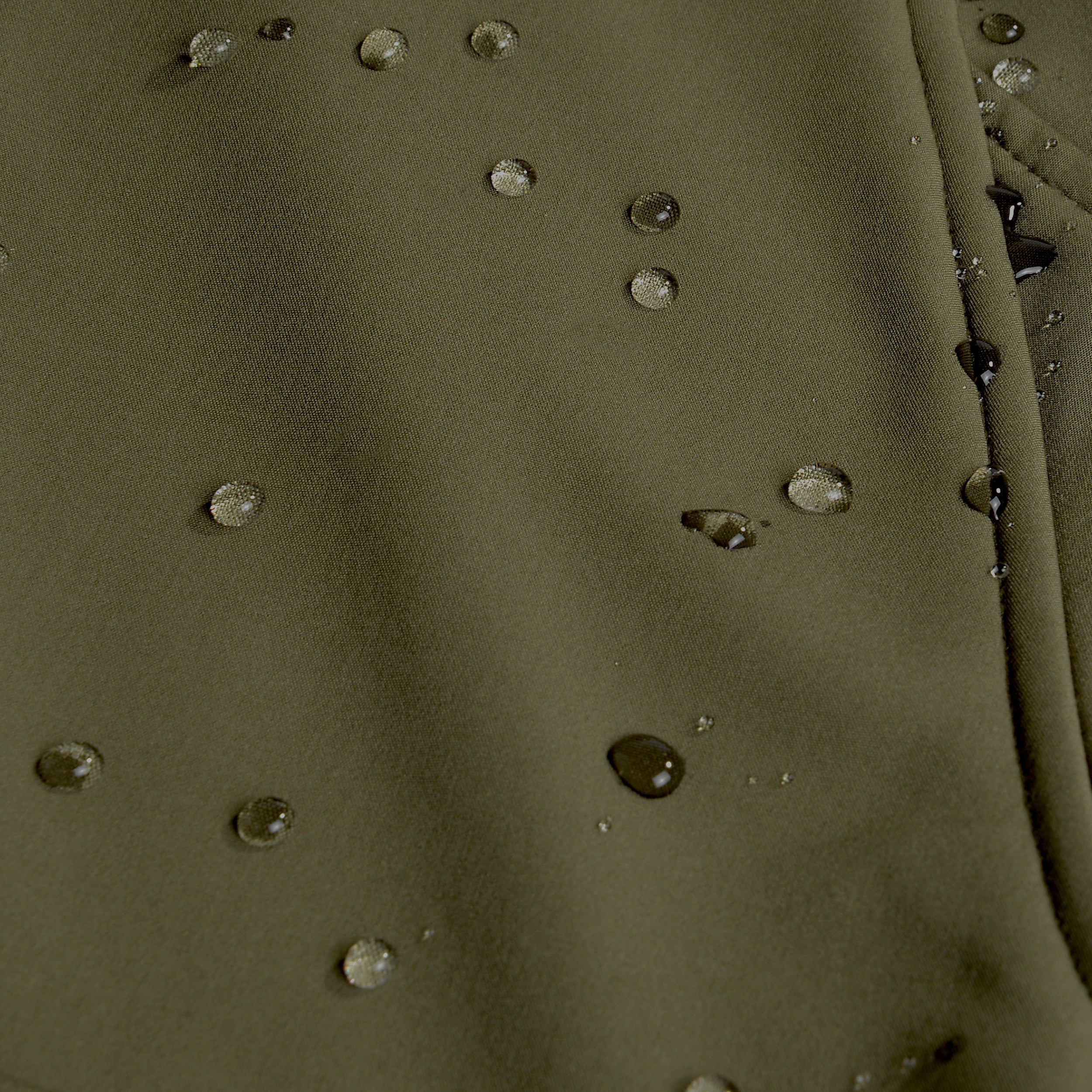 Olive green waterproof hunting jacket fabric with beaded water droplets, ideal for outdoor gear and wet weather.