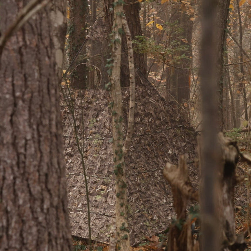 Camouflage hunting blind in forest, leaf-patterned concealment for deer hunting