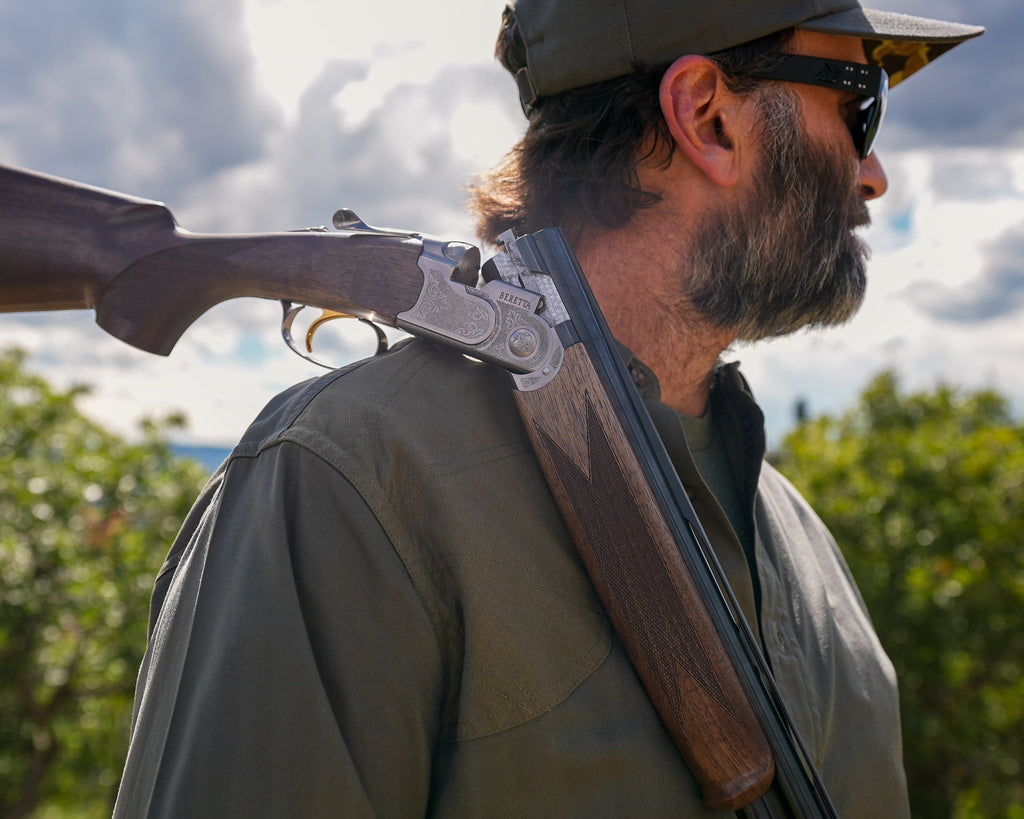 Shotgun resting on the shoulder patch of the Ranger Green Jack Carr Hunters Shirt