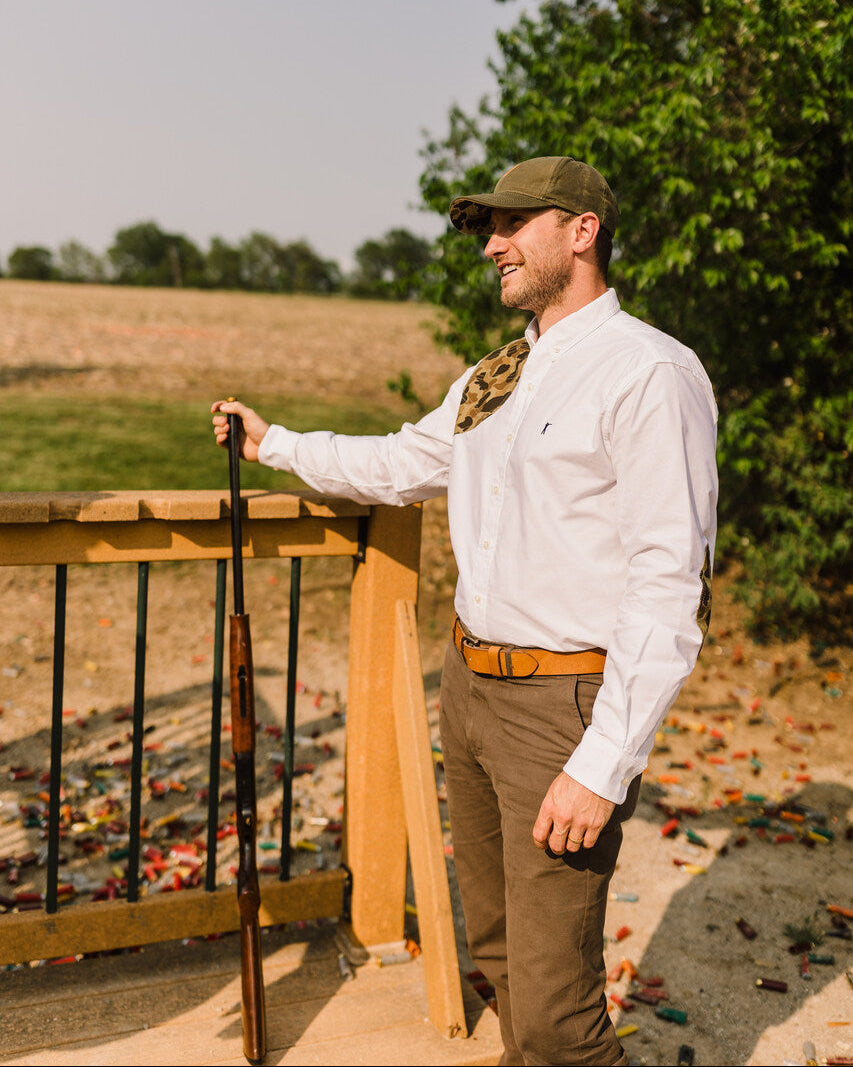 Man in the White Oxford Sportsmans Shirt holding a shotgun at a sporting clays stand
