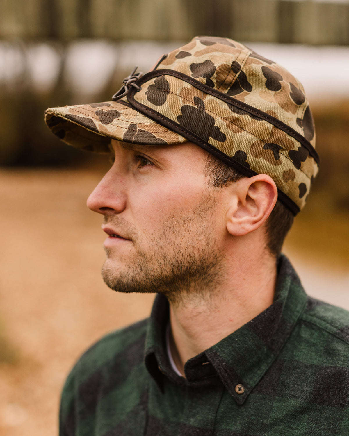 Man in profile wearing the Stormy Kromer x Ball and Buck Original Cap in Original Camo