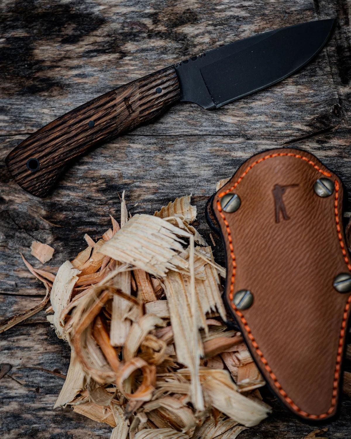 Winkler Huntsman Knife and leather sheath on a log with wood shavings