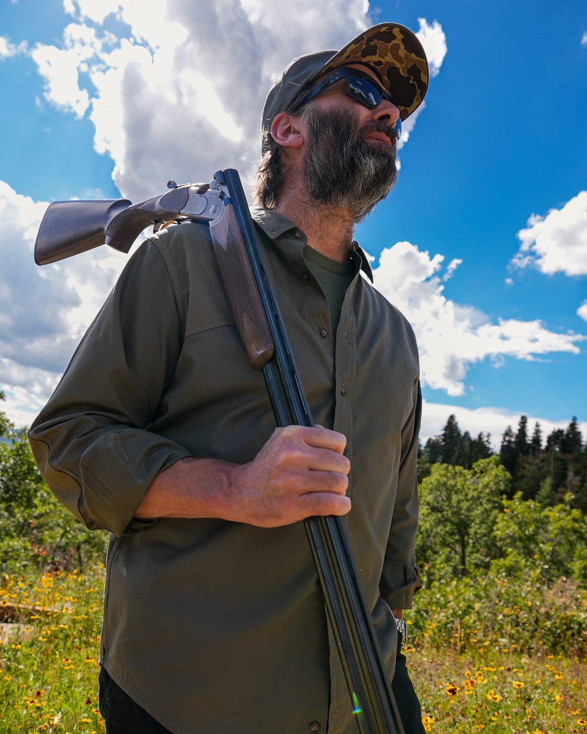 Hunter carrying a shotgun over his shoulder in the Ranger Green Jack Carr Hunters Shirt