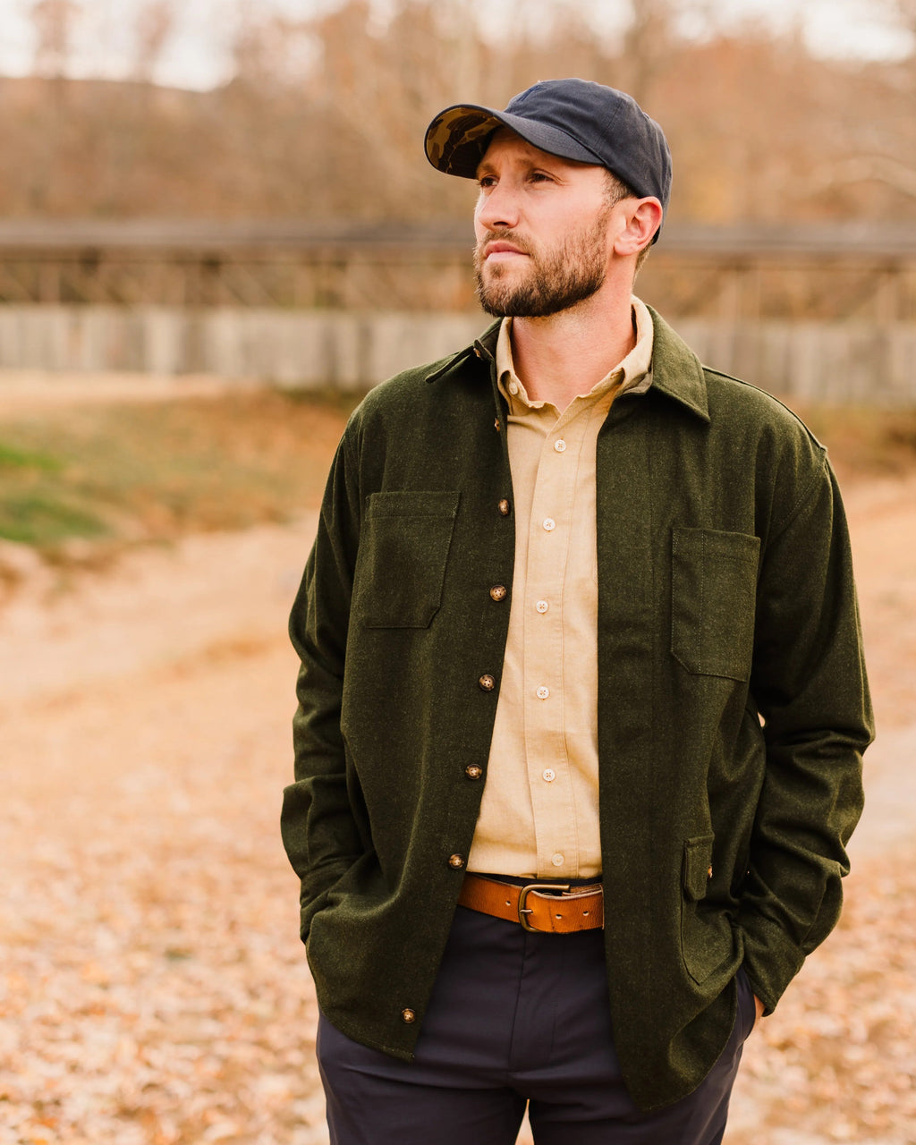 Man in a navy cap wearing the Loden Green Mariners Overshirt open over a tan shirt