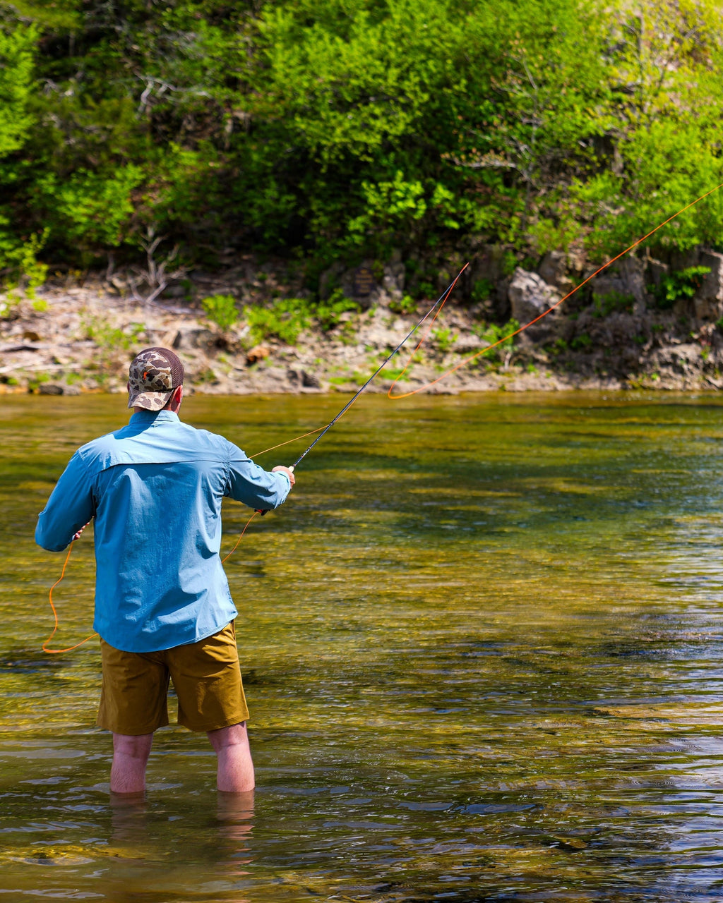 Angler wading a clear stream casting the Scott Centric fly rod