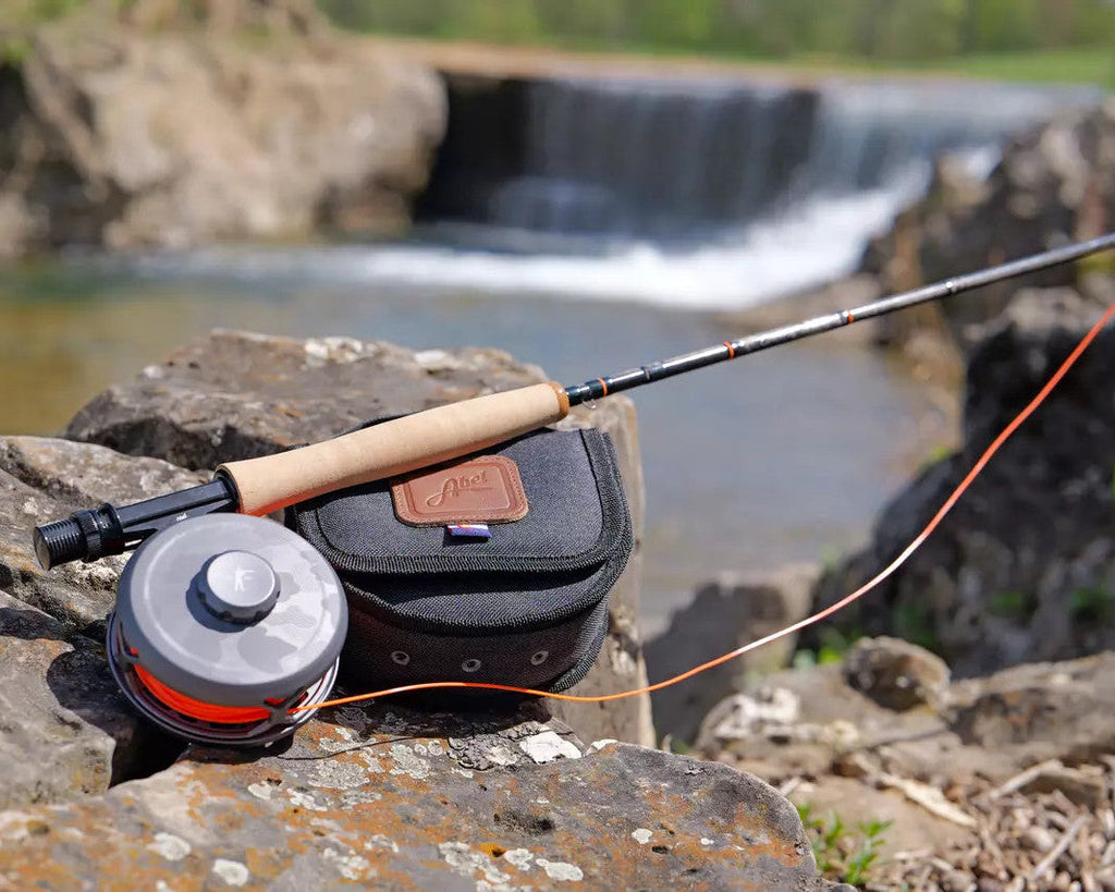 Scott x Ball and Buck Centric fly rod and reel resting on rocks below a small waterfall