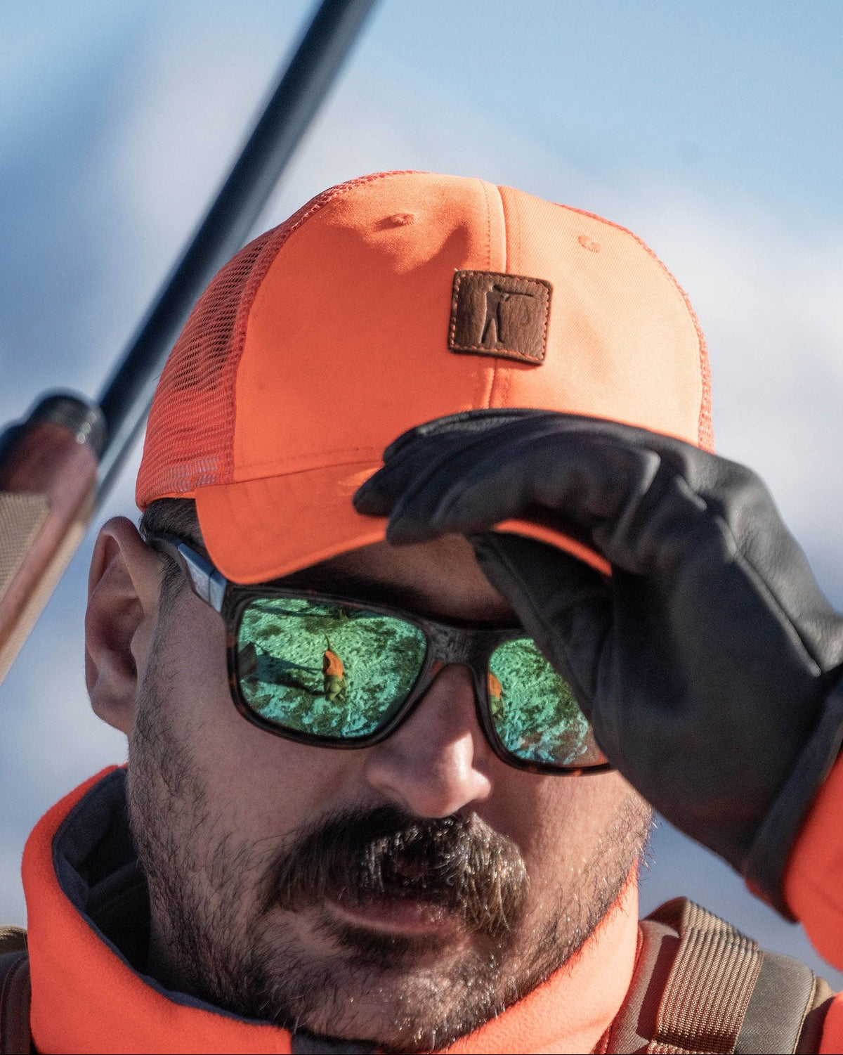 Hunter with green shooting glasses wearing the blaze orange Arthur Snapback Upland Edition