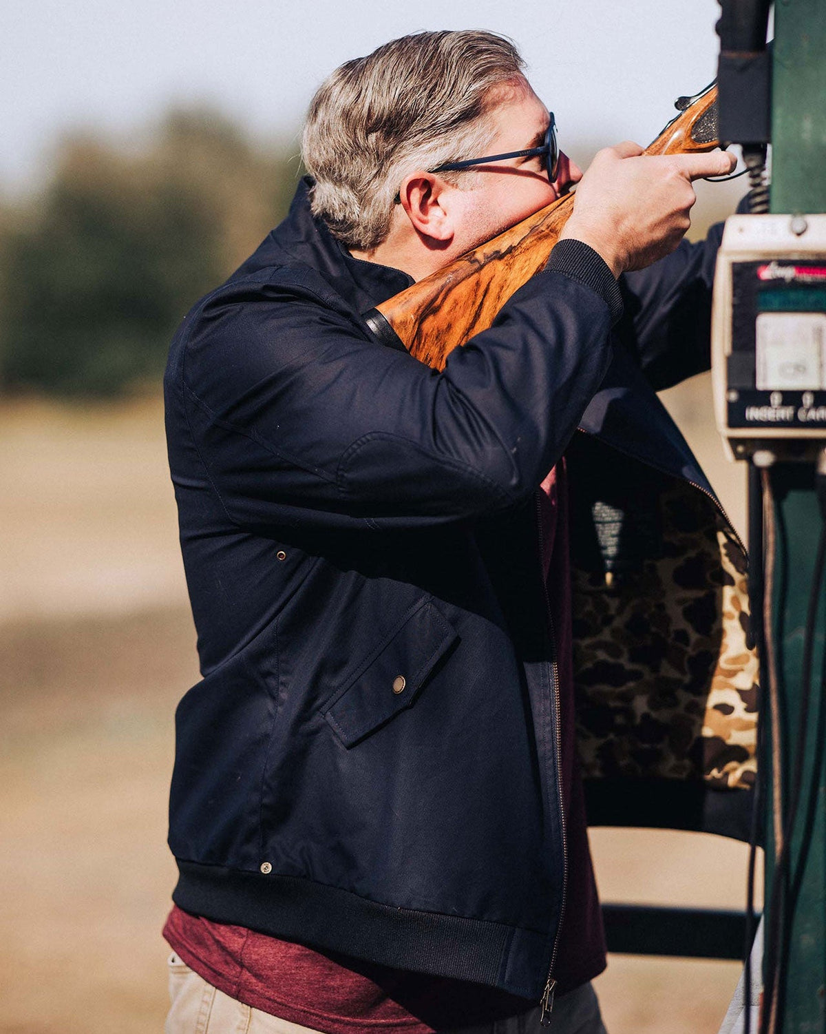 Shooter in the Navy Blue Harrington Jacket at a sporting clays station