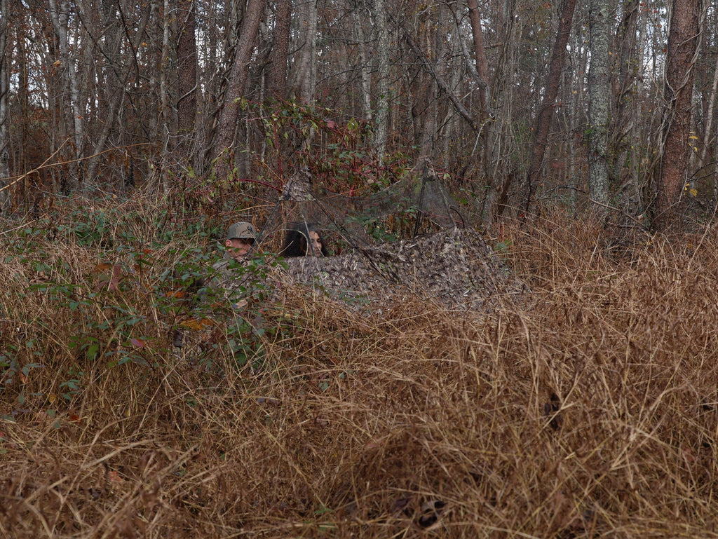 Camo hunting blind in woodland, concealing two hunters for deer or turkey hunting