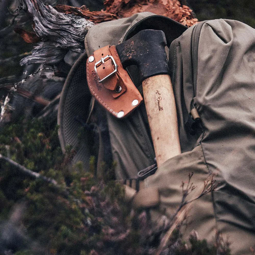 Hunting axe with leather sheath attached to backpack, ideal for outdoor adventures and wilderness survival.