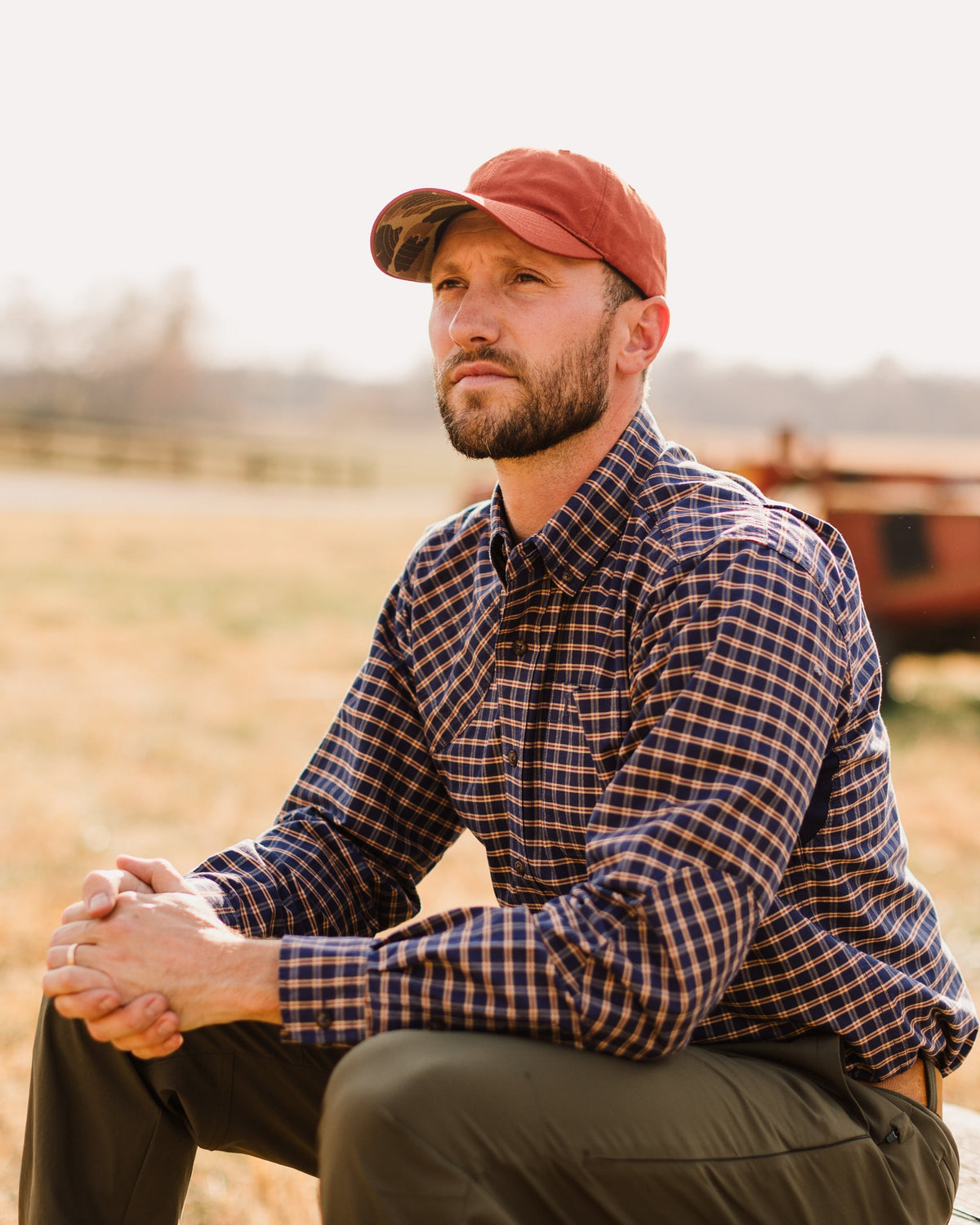 Burnt Orange Arthur Core Hat worn while kneeling in a pasture