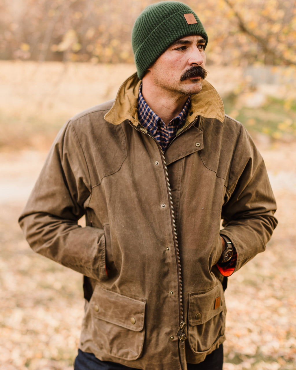 Man in a green beanie wearing the Dark Oak Upland Jacket in a fall woods