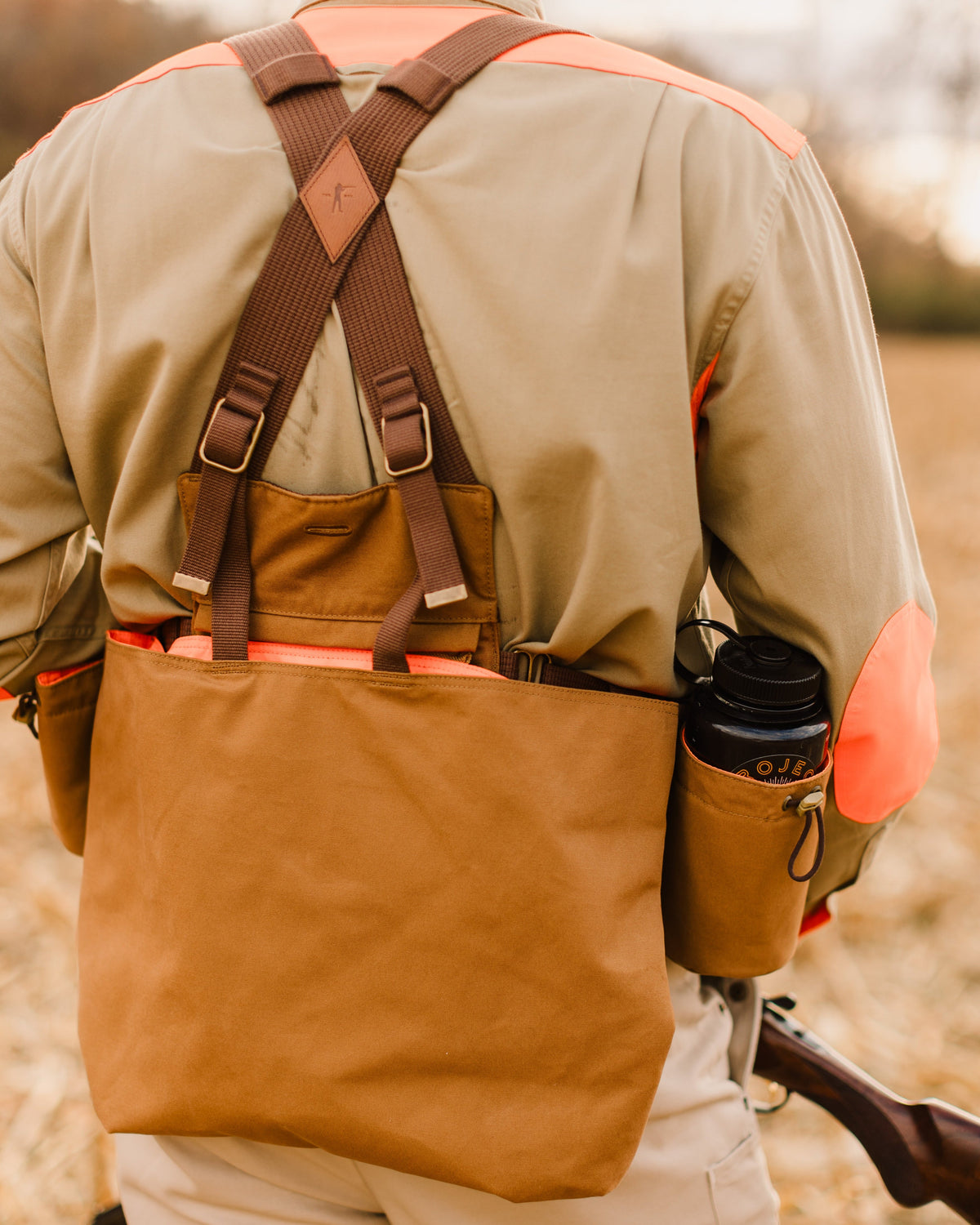 Rear three-quarter view of the Signature Canvas Strap Vest worn with a water bottle
