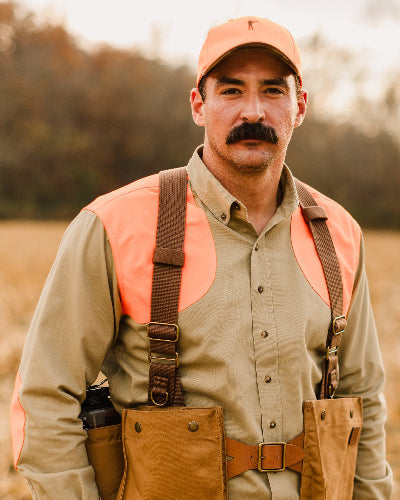 Hunter wearing the Signature Canvas Strap Vest and blaze orange cap, front view in the field