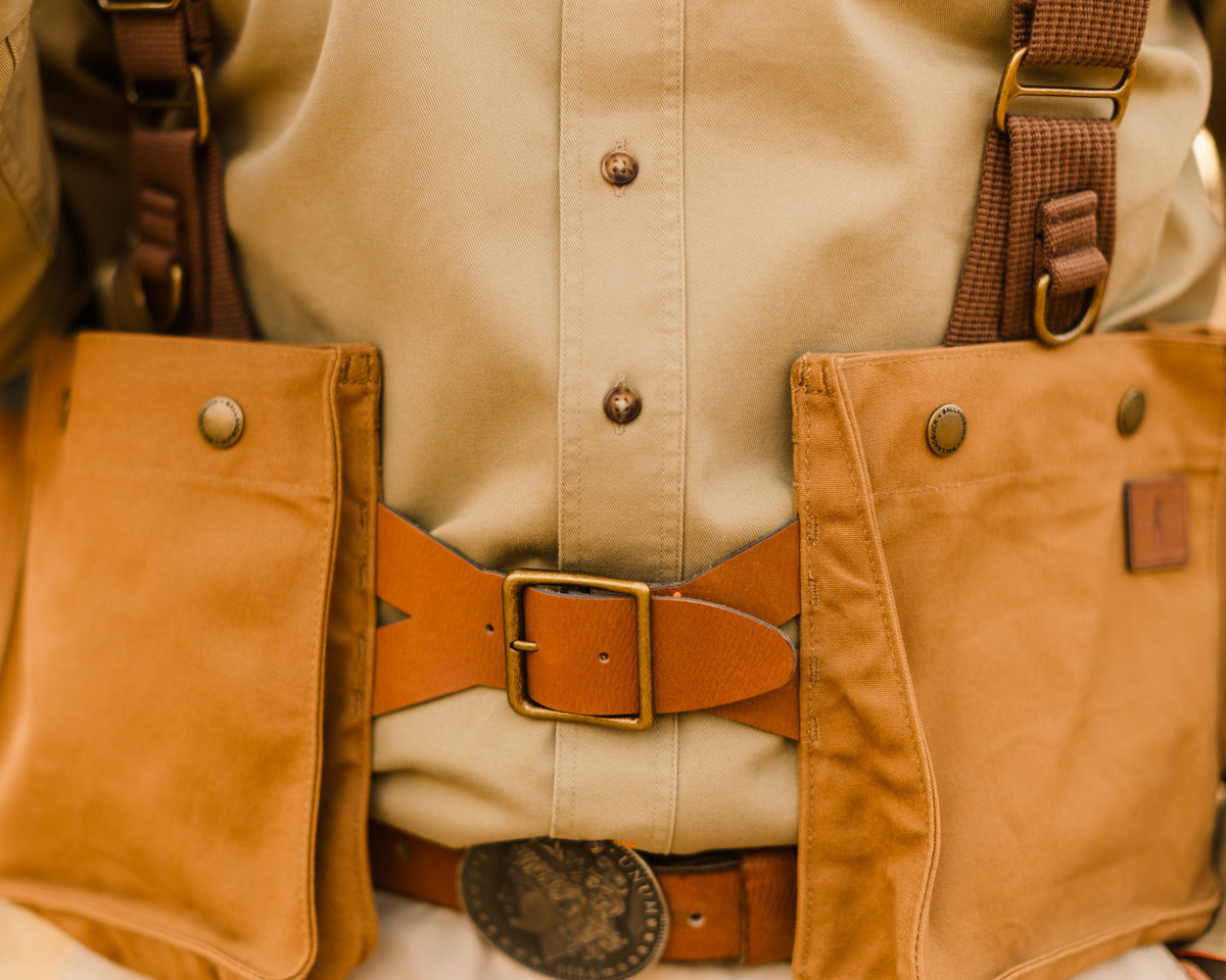 Leather belt closure and front shell pockets on the Signature Canvas Strap Vest worn over a field shirt