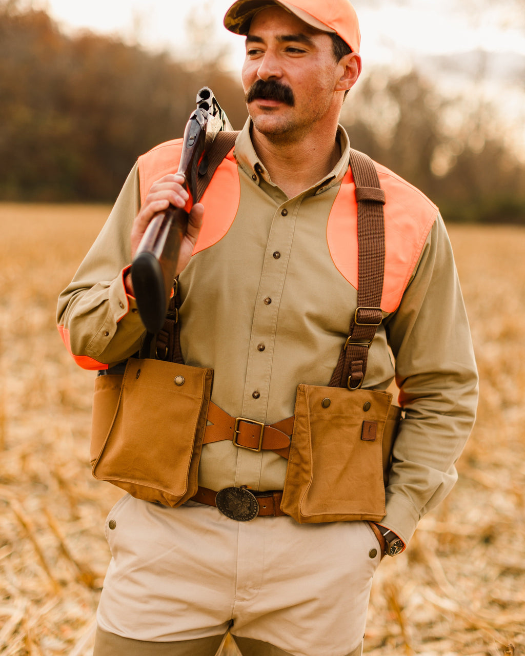 Upland hunter holding a shotgun while wearing the Signature Canvas Strap Vest in a corn field