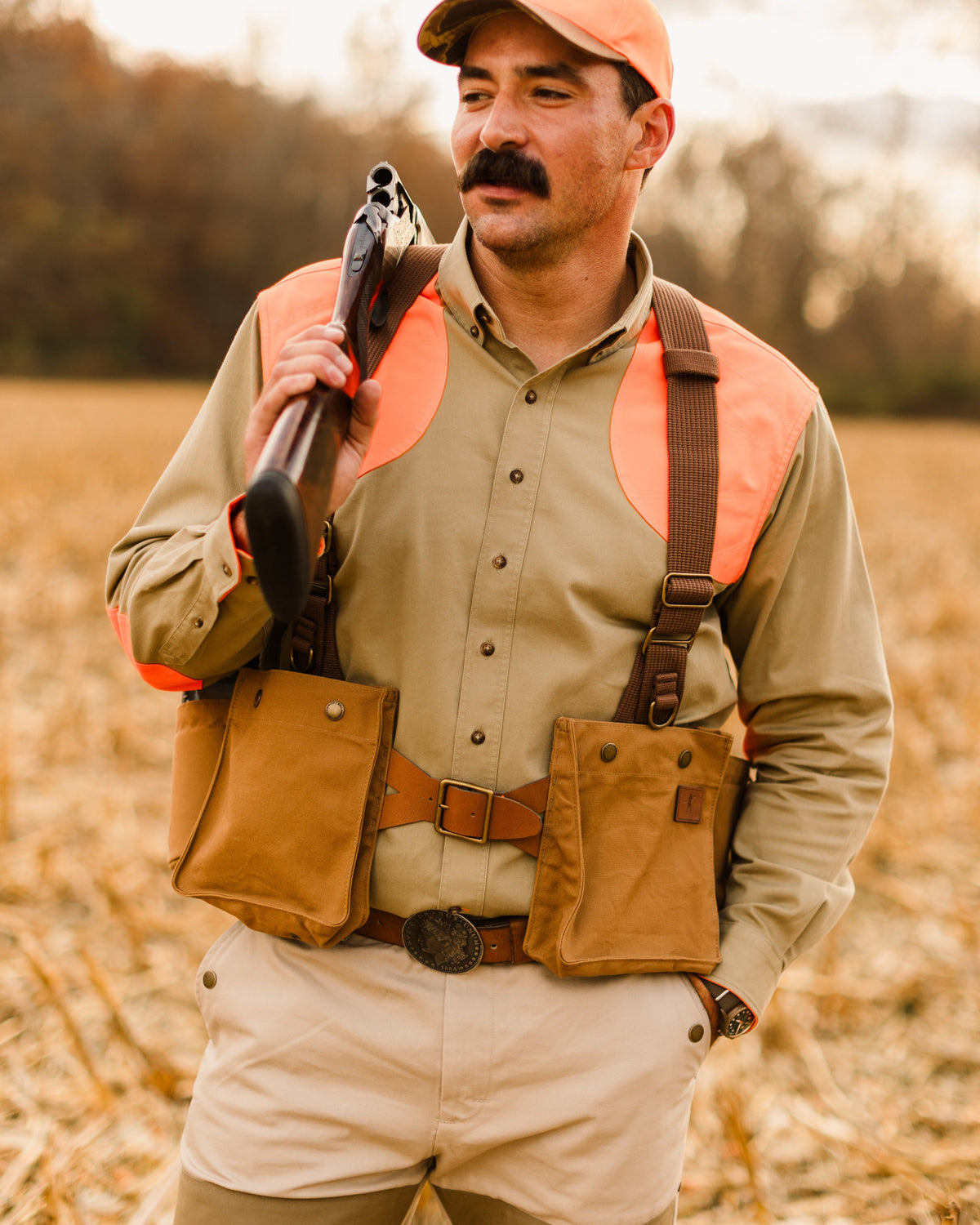 Upland hunter holding a shotgun while wearing the Signature Canvas Strap Vest in a corn field