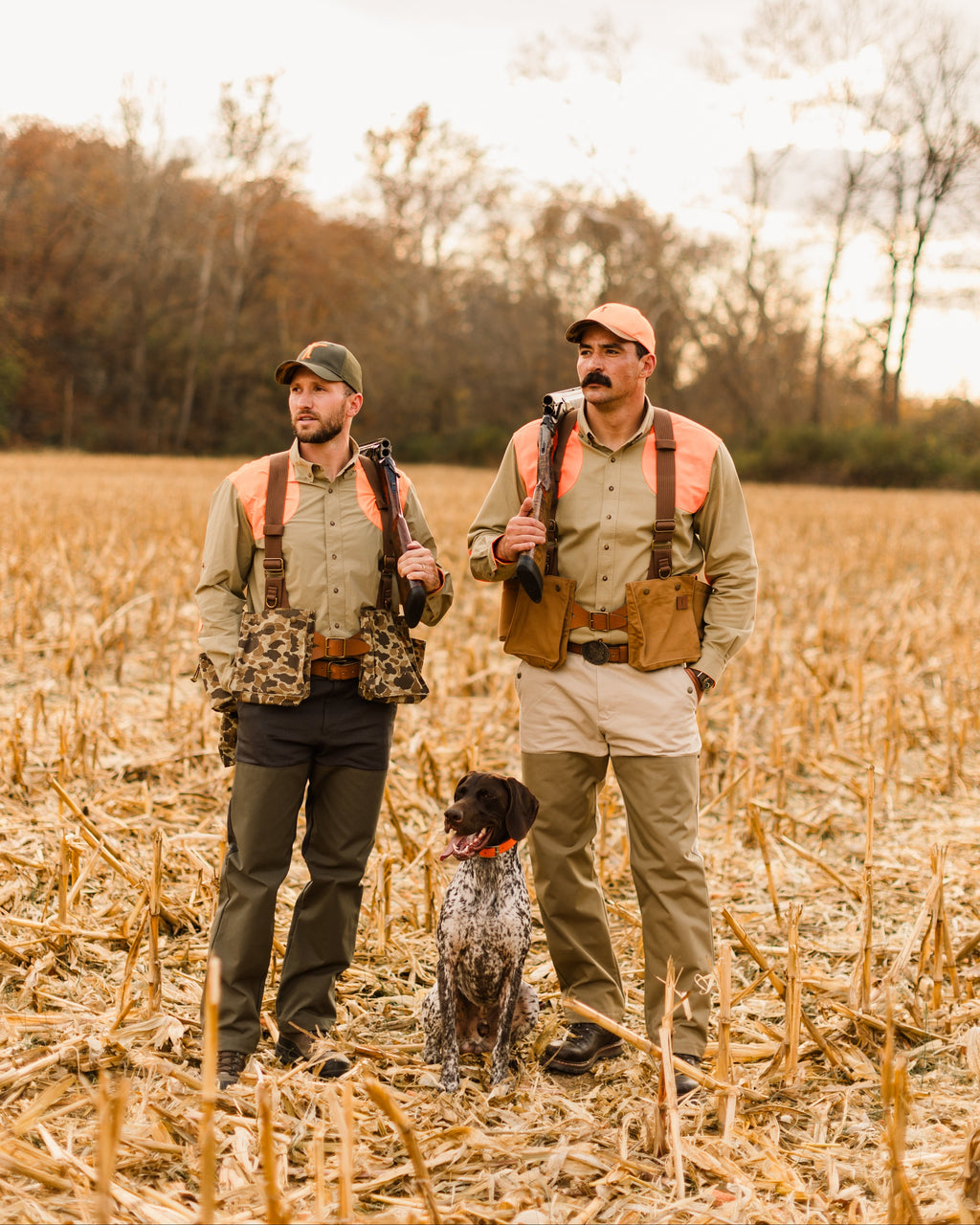 Two hunters and a bird dog in a cut field, one wearing an Arthur Core Snapback