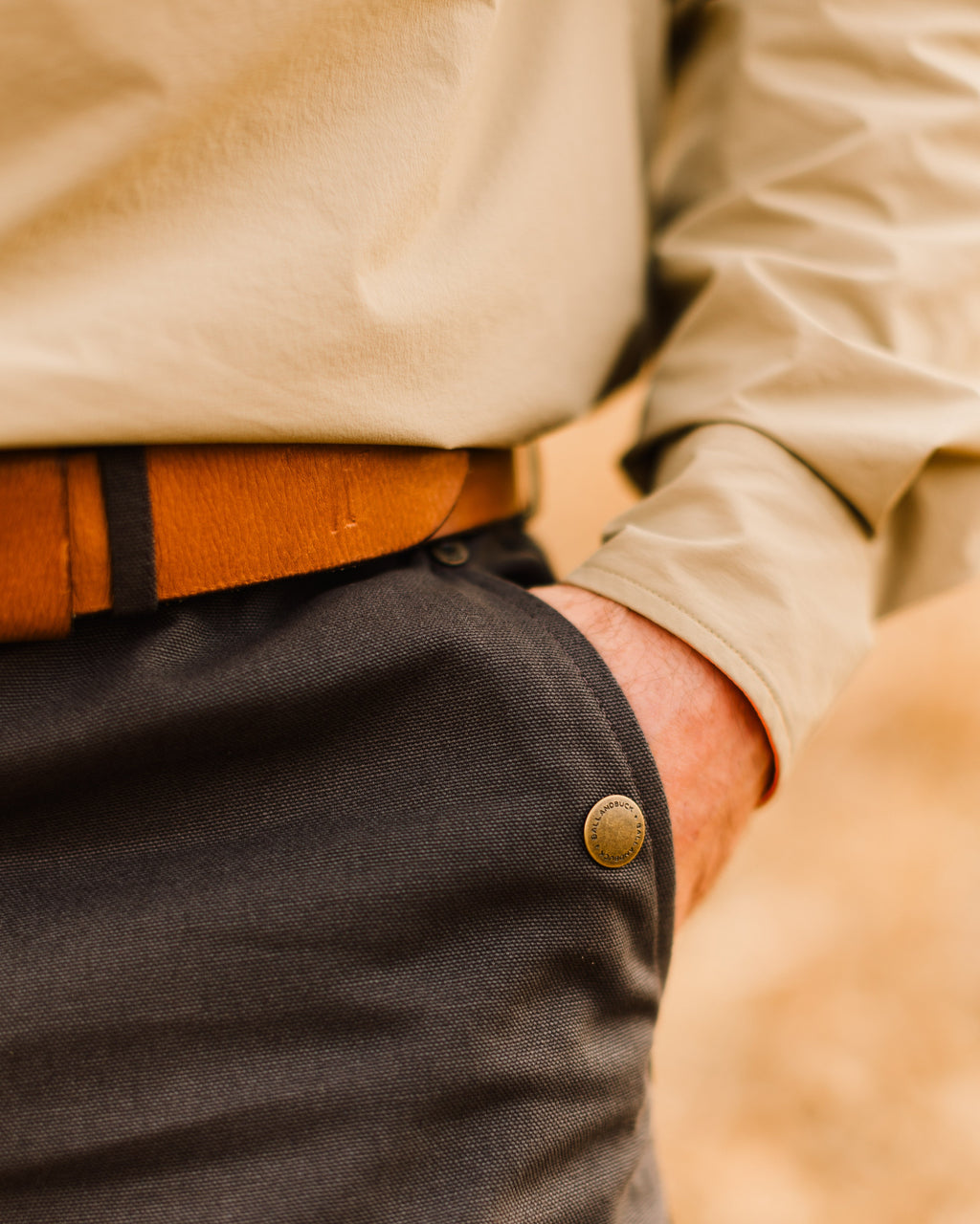 Close-up of the Signature Leather belt and brass buckle worn with field pants