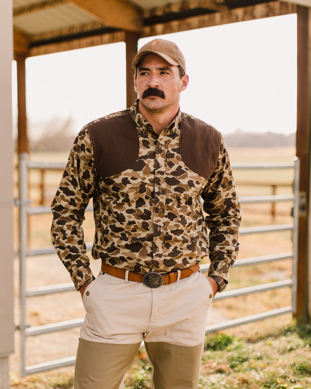 Man in the Original Camo Sportsmans Shirt FG and khaki pants under a barn shed