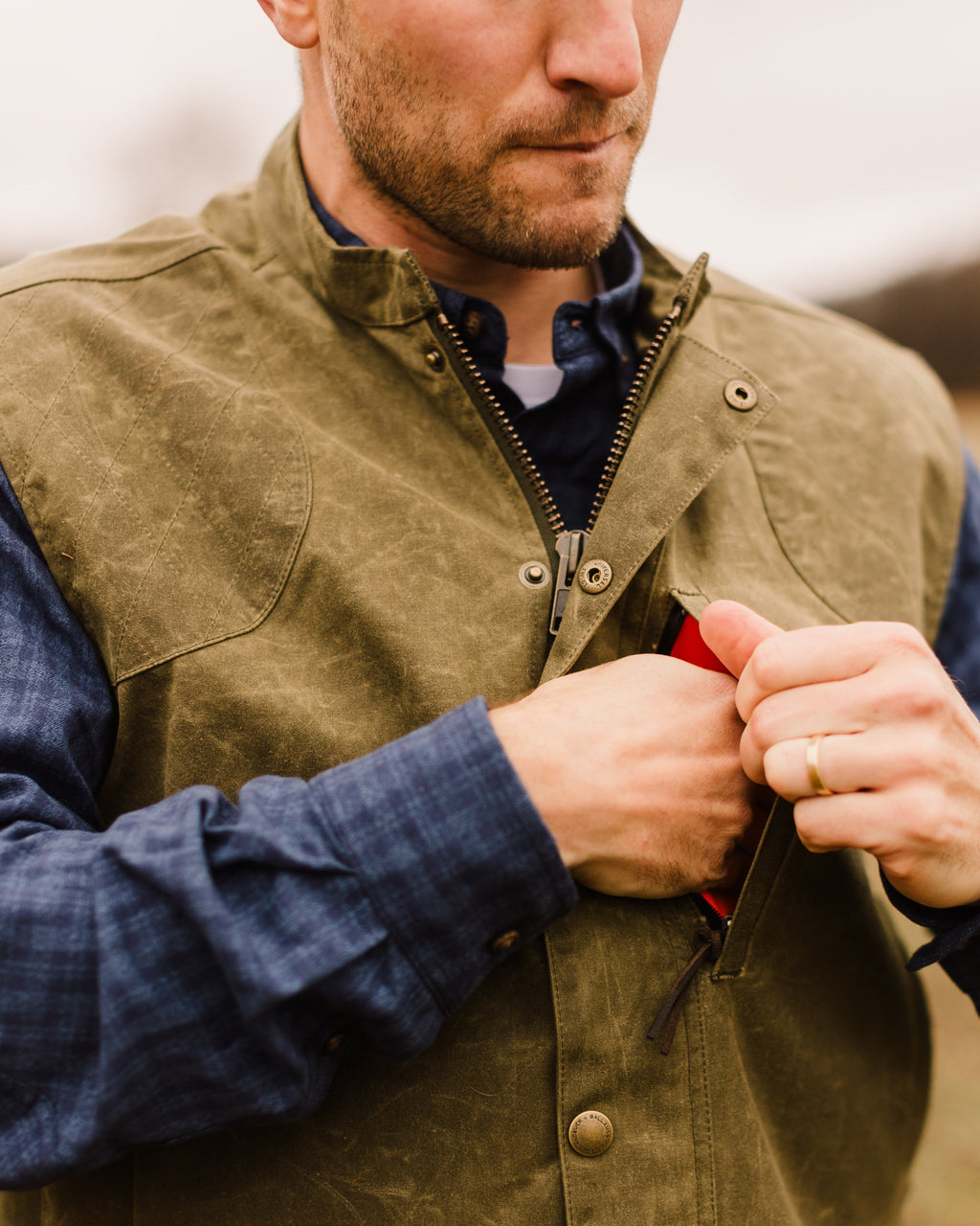 Close-up of the front zipper being pulled on the Olive Upland Vest