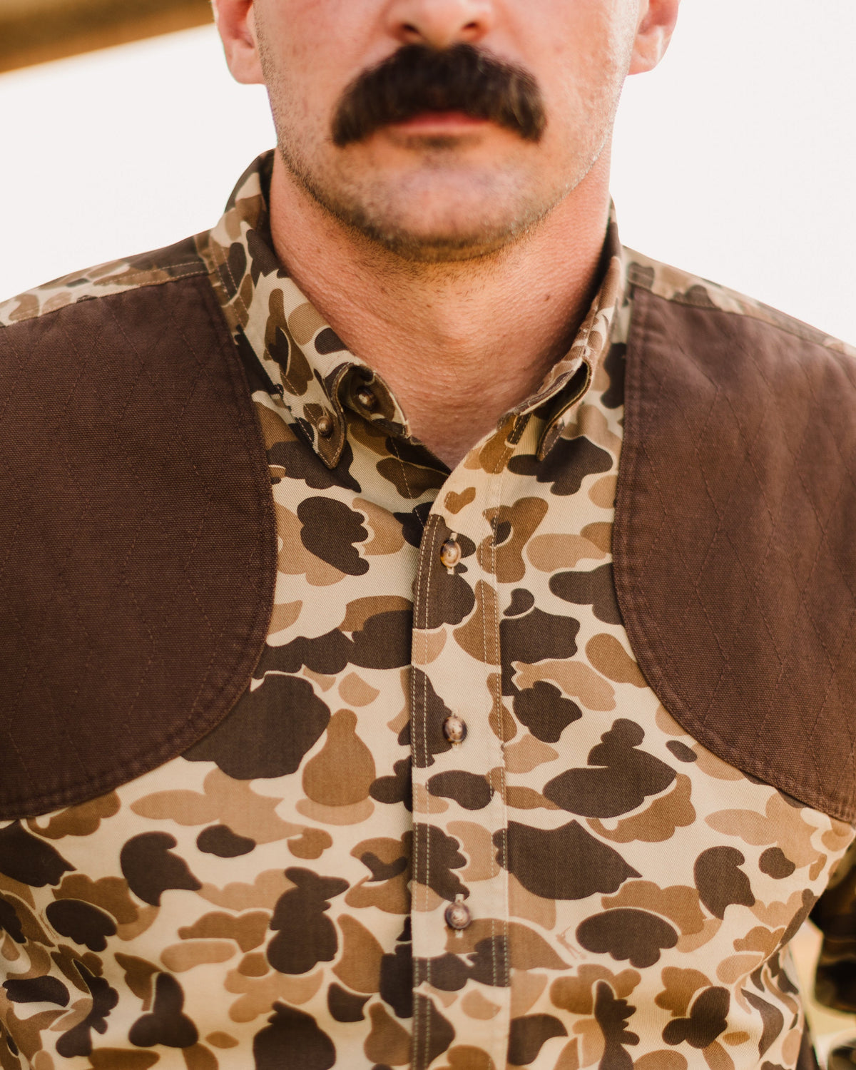 Close-up of a man wearing the Original Camo Sportsmans Shirt FG with brown quilted shoulders