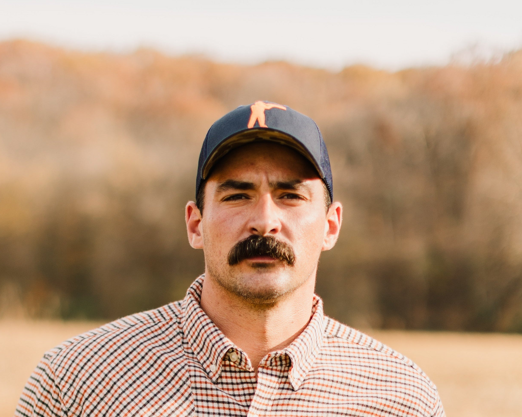 Man wearing the Navy Arthur Core Snapback with a check shirt in a field