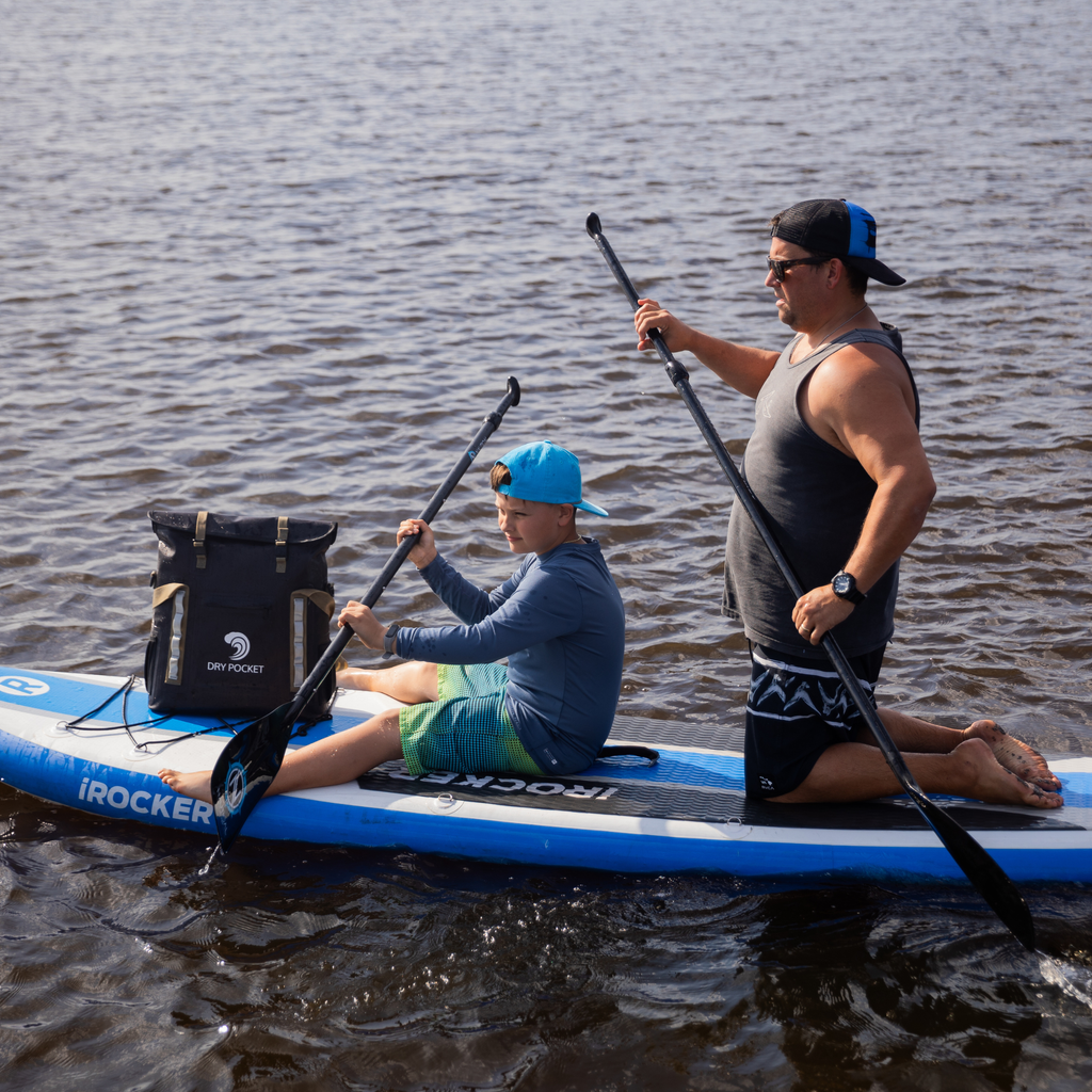 iROCKER inflatable paddle board with dry bag, used by man and boy on water for outdoor recreation
