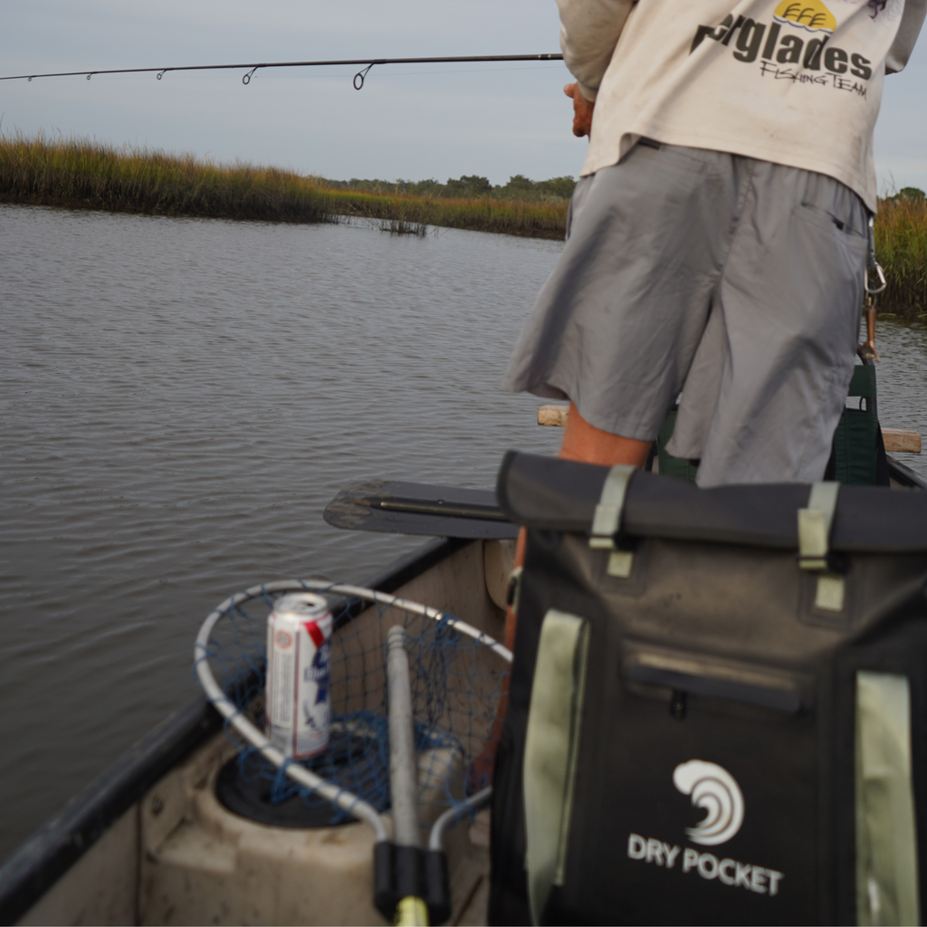 Fishing dry pocket bag on boat with angler casting rod in marsh, gear for outdoor fishing adventures