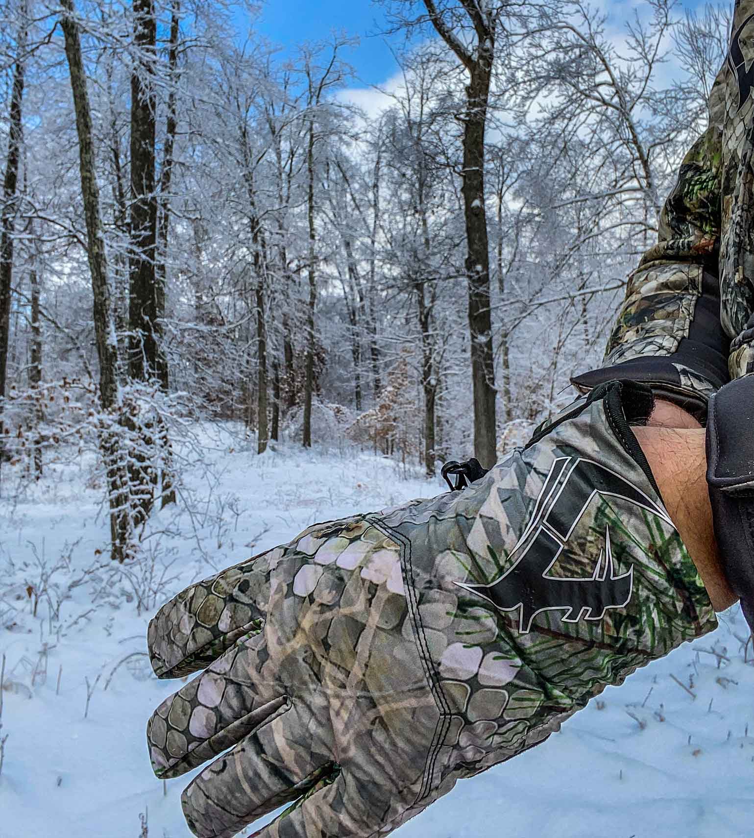 Hunter wearing Vycah Conley insulated camo gloves in snow-covered winter timber