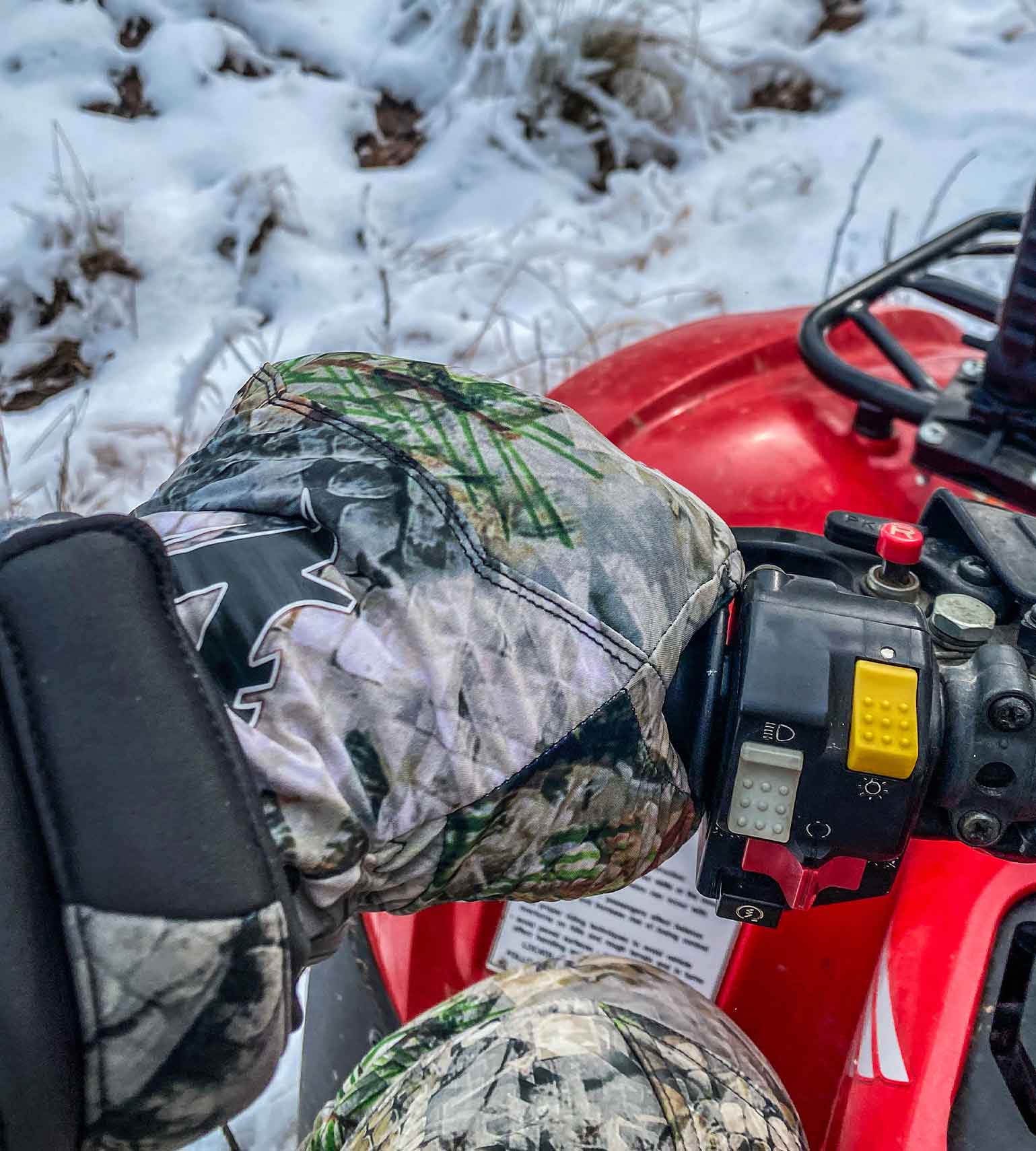 Hunter in Vycah Conley insulated camo gloves gripping an ATV handlebar in the snow