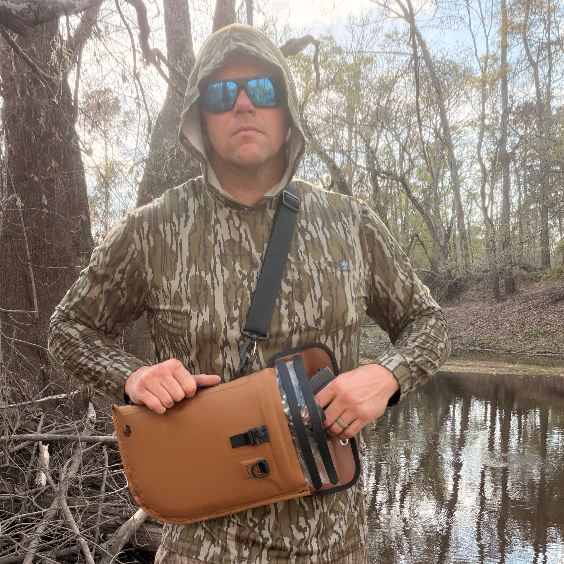 Camo hunting vest with tan waterproof chest pack for outdoor gear storage near water