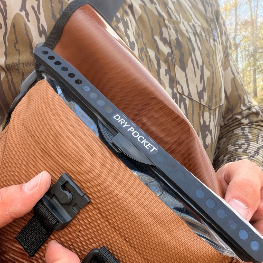 Brown tactical dry pocket pouch with black strap, shown on camo hunting gear for outdoor use.