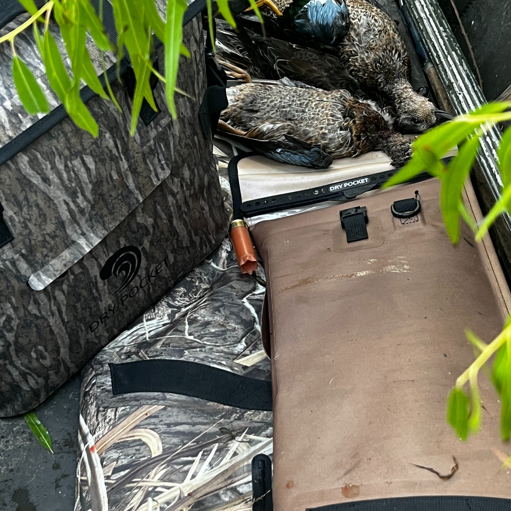 Dry Pocket camo hunting gear with harvested ducks, shotgun shells, and waterproof storage for waterfowl hunts