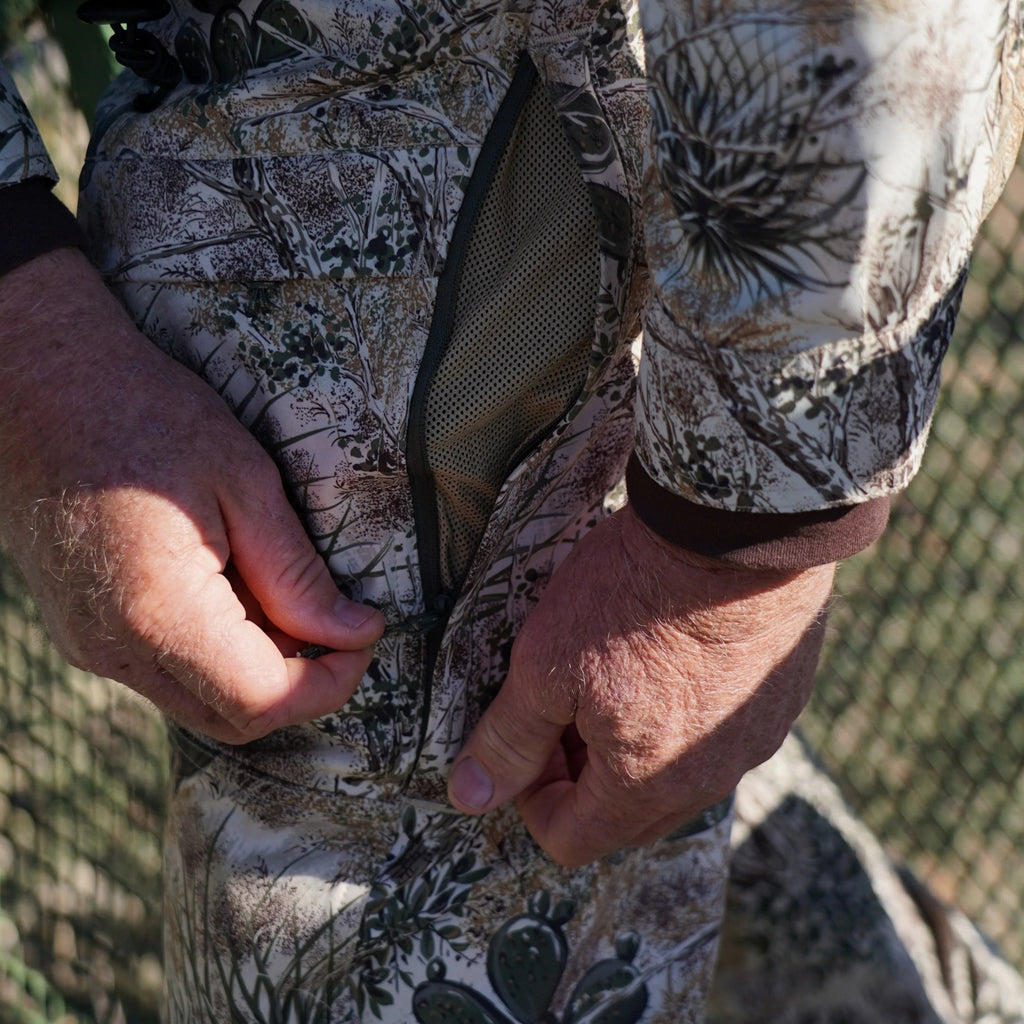 Hunting camo jacket with desert brush pattern, mesh lining, and zippered chest pocket for outdoor gear storage