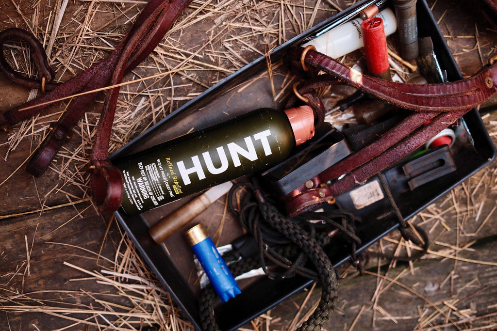 Hunt scent-free deer repellent spray with shotgun shells, leather straps, and outdoor gear in a hunting kit