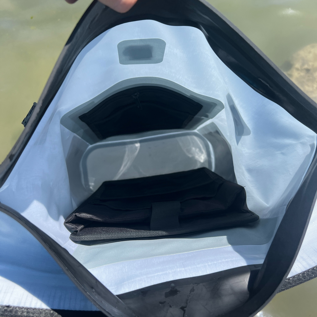 Waterproof dry bag interior with black storage pouch, ideal for fishing and outdoor gear protection on water