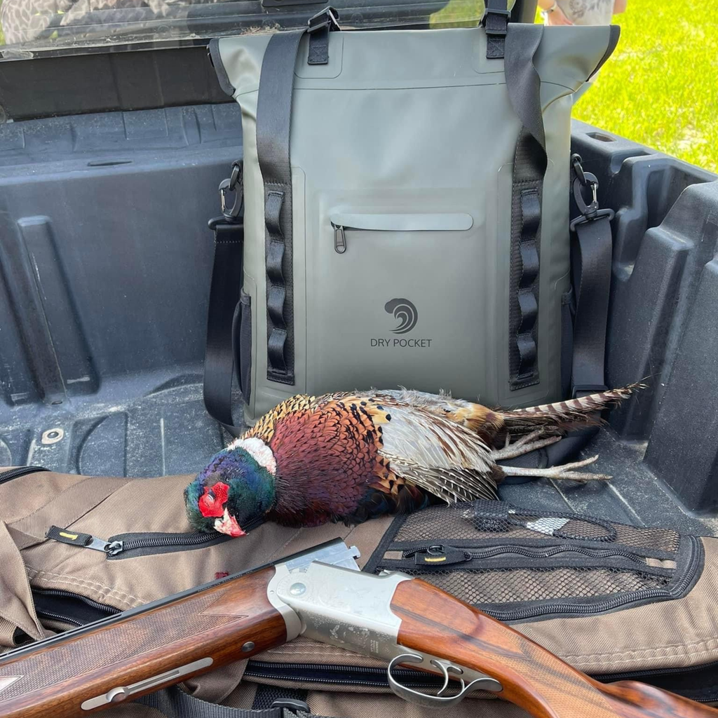Hunting gear: shotgun, pheasant, and Dry Pocket waterproof backpack in truck bed for outdoor adventures.