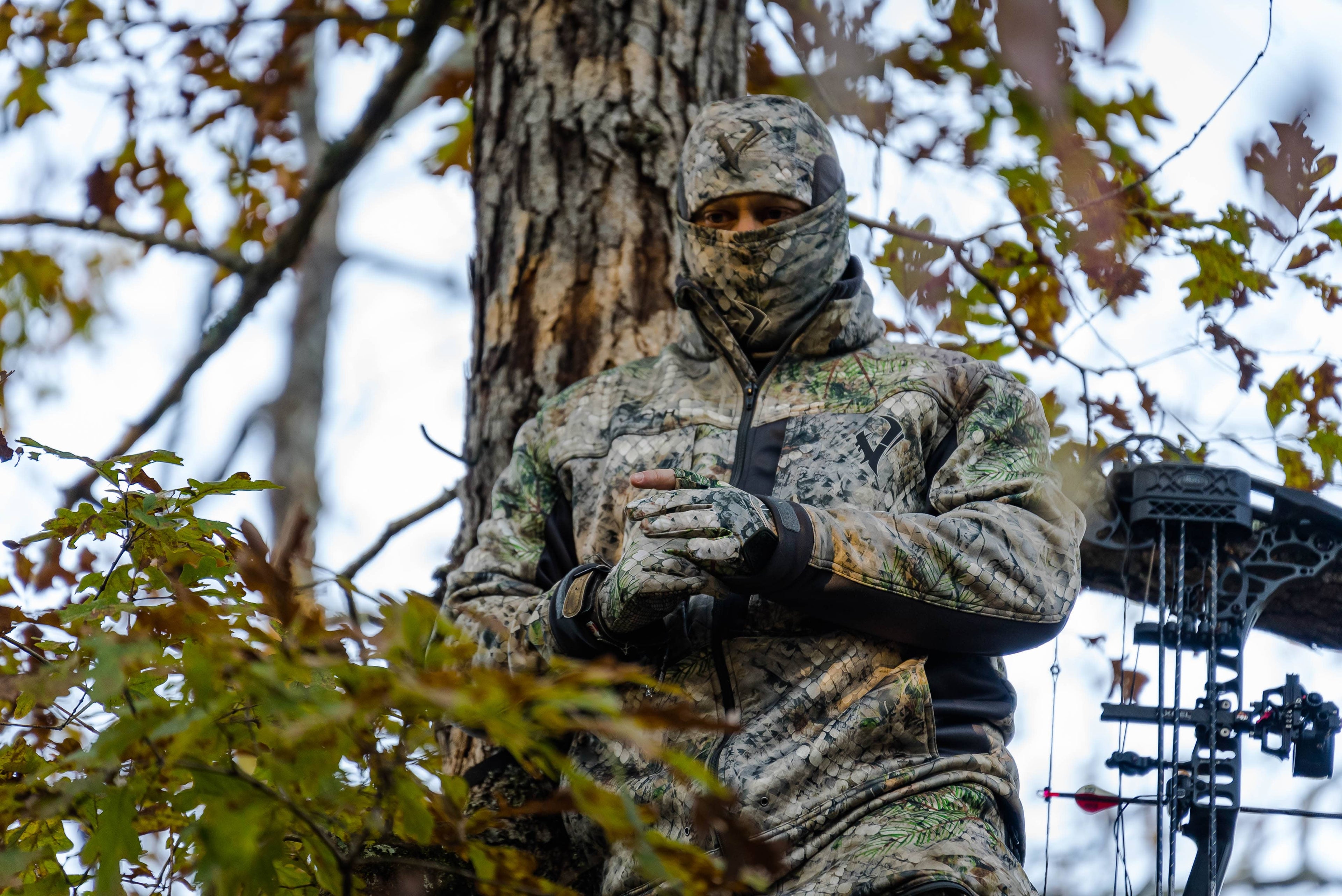 Bowhunter in a treestand wearing a Vycah camo neck gaiter pulled up over his face