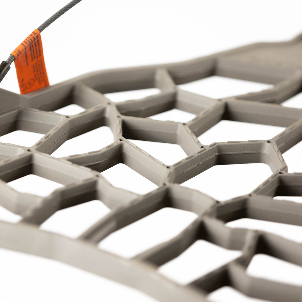 Gray hexagonal hunting blind mesh with orange safety tag and steel cable attachment