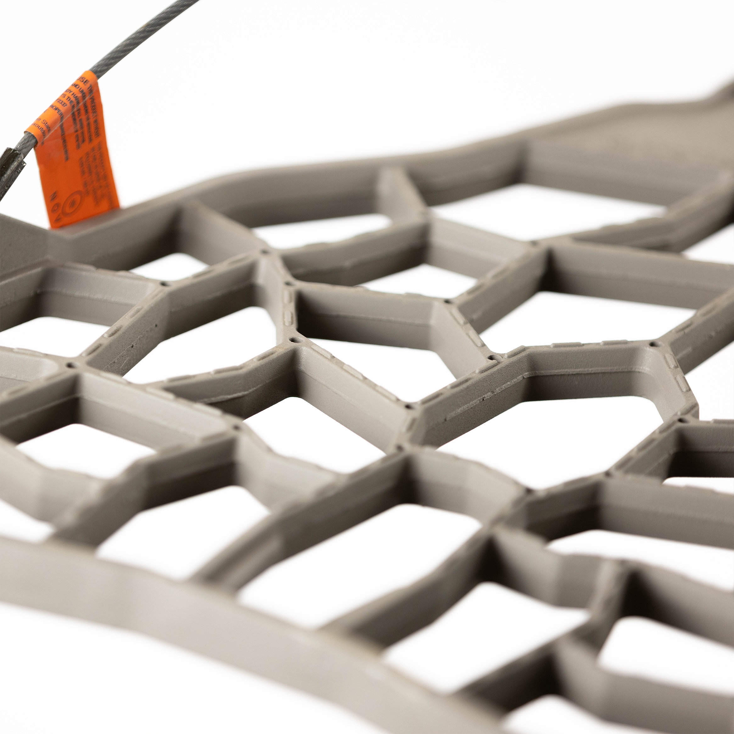 Gray hexagonal hunting blind mesh with orange safety tag and steel cable attachment