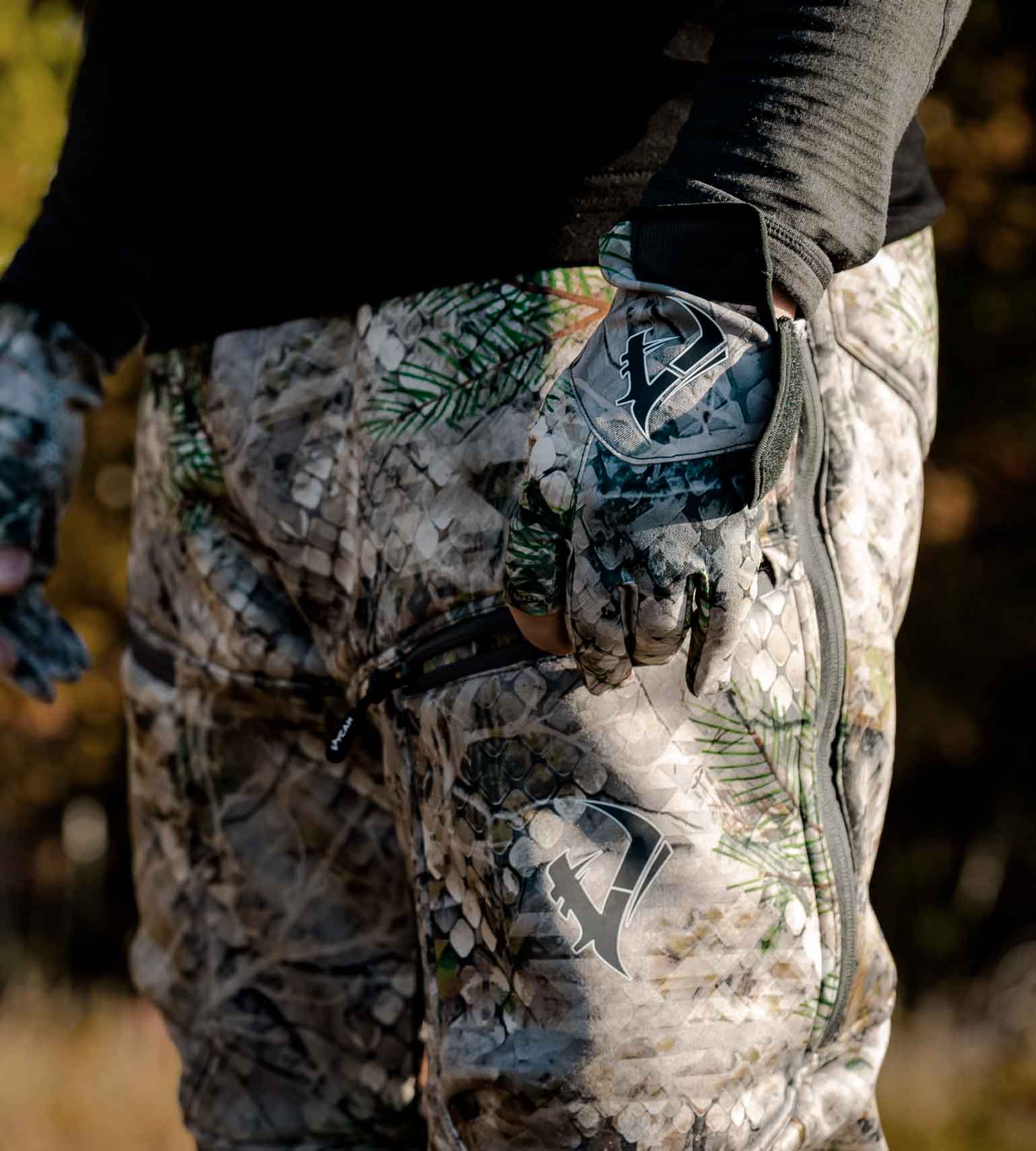 Hunter's hand in a Vycah Huntley fingerless glove resting on Fall camo hunting pants in the field