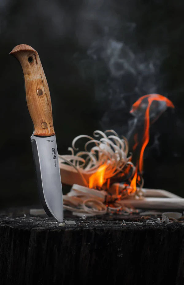 Fixed blade hunting knife with wooden handle beside campfire, ideal for outdoor survival and bushcraft tasks
