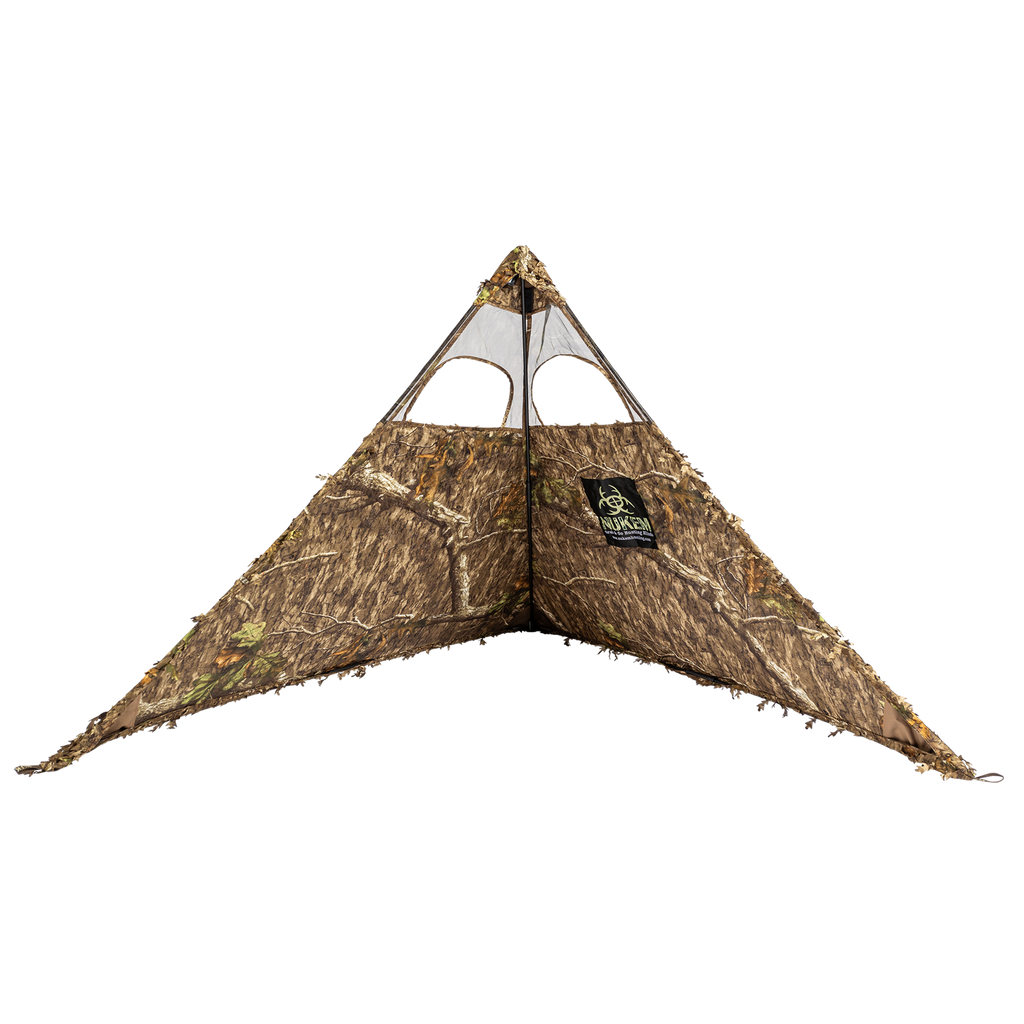 Camo hunting blind with leafy tree pattern, mesh windows, and ground-level concealment for outdoor hunting gear.