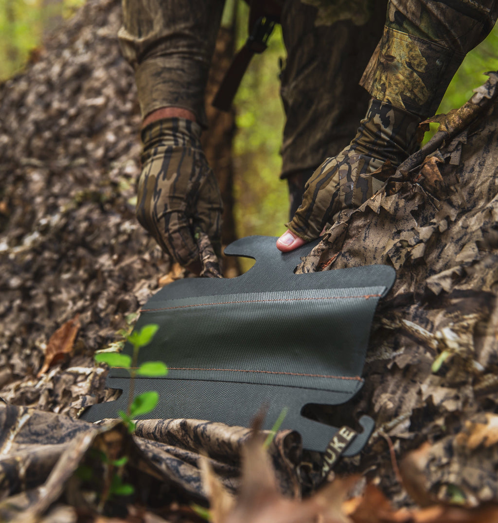 Hunting knee pad with camo gloves in forest, outdoor gear for hunters